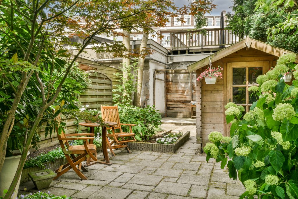 An interlocking patio with grey bricks, featuring a central fire pit and wooden benches